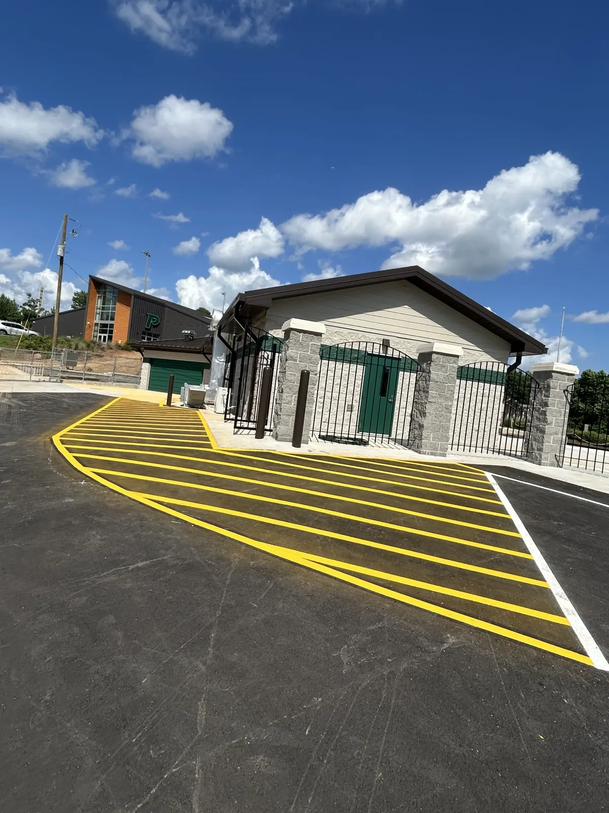Bright yellow crosshatched walkway striping at a school athletic facility